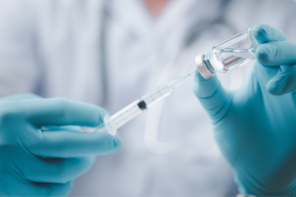 A Doctor holding an injection and a vaccine bottle 